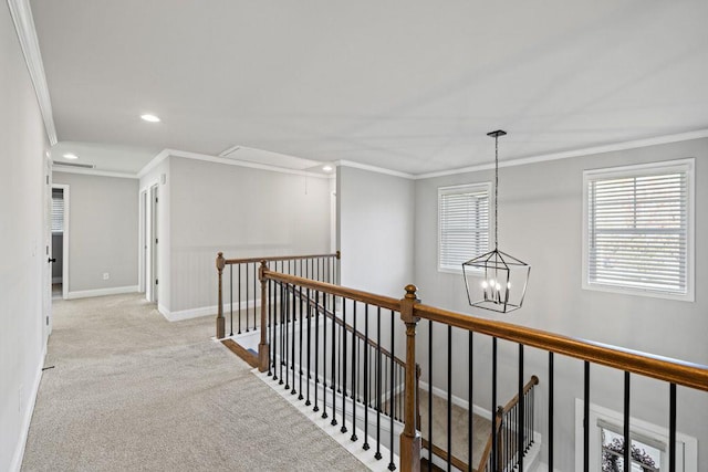 hallway featuring attic access, ornamental molding, carpet flooring, an upstairs landing, and baseboards