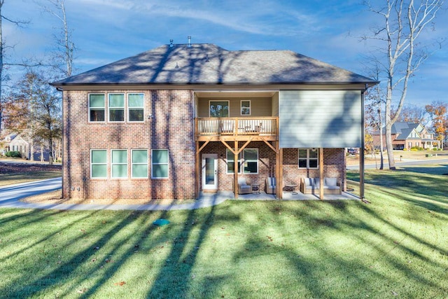 back of house featuring a balcony, brick siding, a shingled roof, a yard, and a patio area