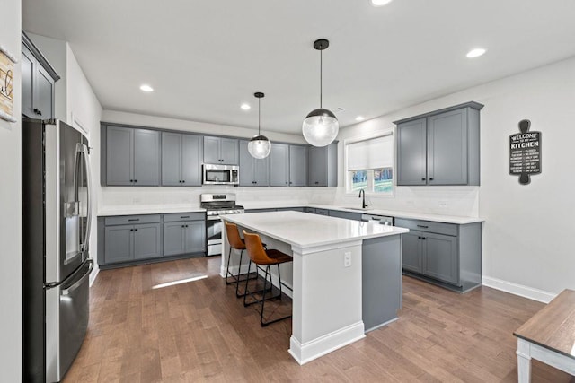 kitchen with stainless steel appliances, a center island, a sink, and gray cabinetry