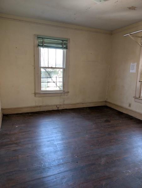 unfurnished room with ornamental molding and dark wood-type flooring