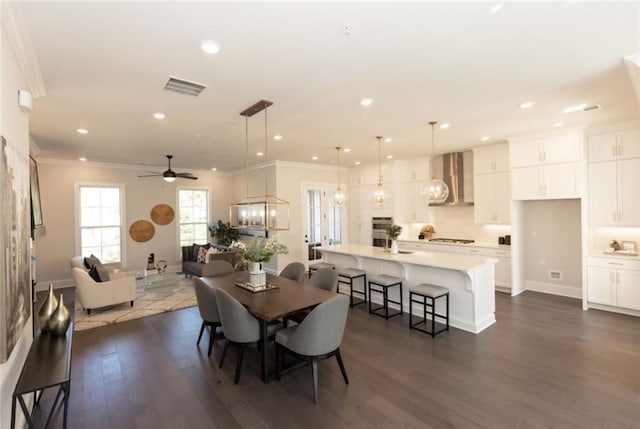 dining space with ornamental molding, dark wood-type flooring, and ceiling fan with notable chandelier