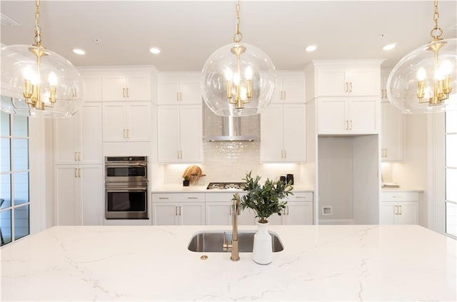 kitchen featuring appliances with stainless steel finishes, light stone counters, tasteful backsplash, white cabinetry, and hanging light fixtures