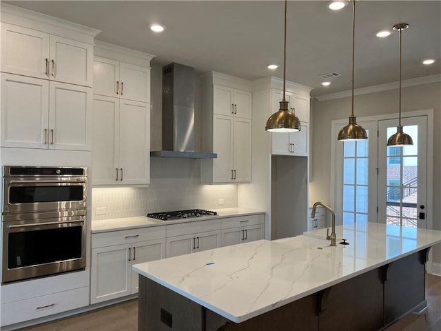 kitchen with dark hardwood / wood-style floors, backsplash, wall chimney range hood, and an island with sink