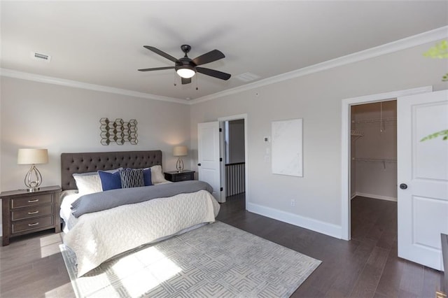 bedroom with a closet, ceiling fan, a spacious closet, crown molding, and dark hardwood / wood-style flooring