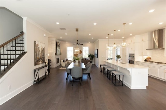 dining room with sink, ceiling fan with notable chandelier, dark hardwood / wood-style flooring, and ornamental molding