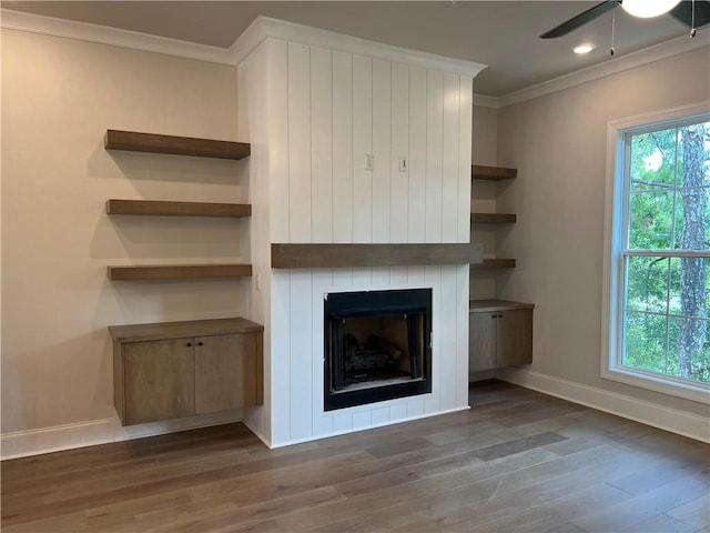 unfurnished living room with ceiling fan, ornamental molding, dark wood-type flooring, and a fireplace