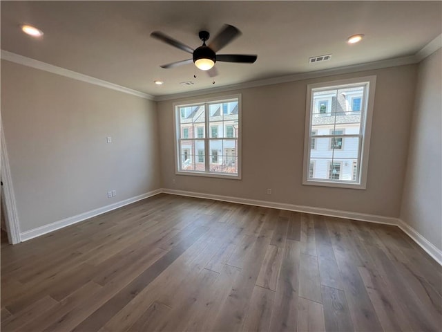 spare room featuring dark hardwood / wood-style flooring, ceiling fan, ornamental molding, and plenty of natural light