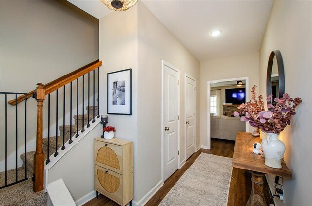 corridor with baseboards, stairs, and dark wood-type flooring