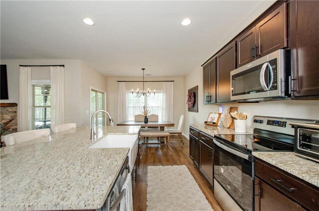 kitchen featuring light stone countertops, dark brown cabinetry, recessed lighting, stainless steel appliances, and dark wood-style flooring