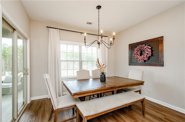 dining area with an inviting chandelier, wood finished floors, a healthy amount of sunlight, and visible vents