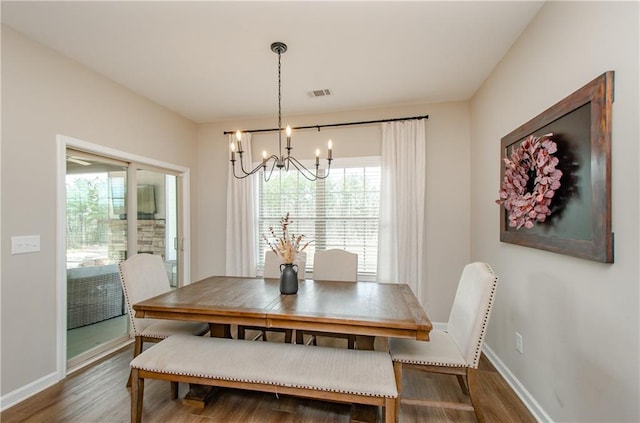 dining space with visible vents, baseboards, an inviting chandelier, and wood finished floors