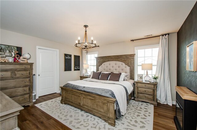 bedroom featuring dark wood-style floors, visible vents, and a notable chandelier