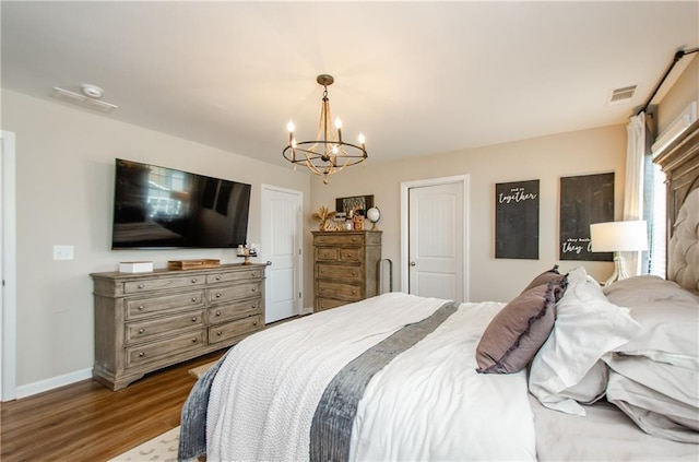 bedroom featuring visible vents, baseboards, an inviting chandelier, and wood finished floors