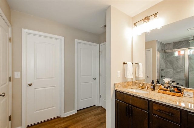 bathroom featuring visible vents, vanity, wood finished floors, and a shower stall