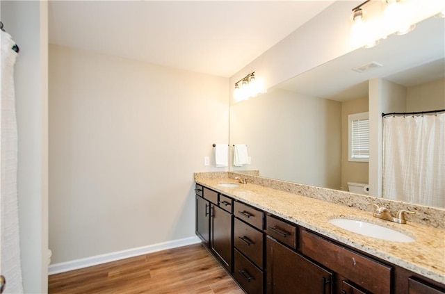 bathroom with wood finished floors, baseboards, visible vents, a sink, and toilet