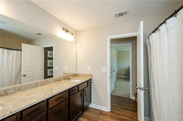 full bath with vanity, wood finished floors, visible vents, and baseboards