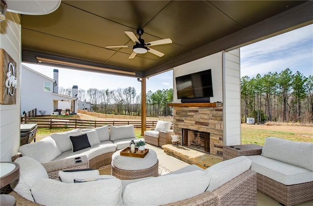 view of patio / terrace with an outdoor living space with a fireplace, fence, and ceiling fan