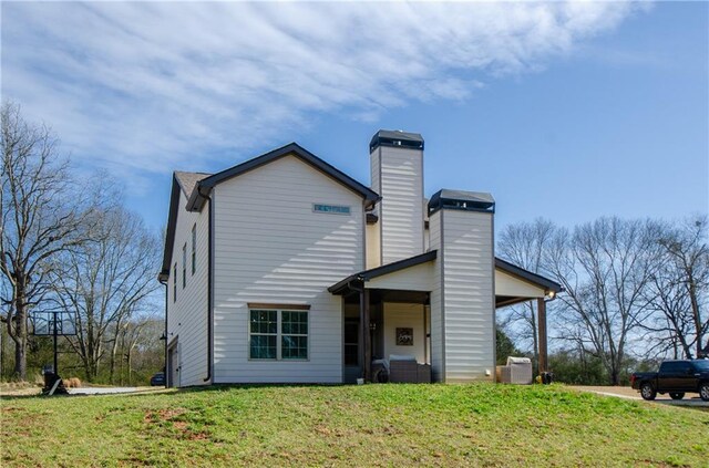 back of house with a lawn and a chimney