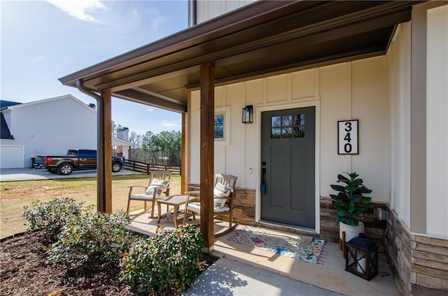 entrance to property featuring stone siding, a porch, and board and batten siding