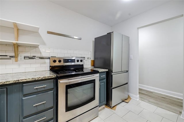 kitchen featuring gray cabinetry, tasteful backsplash, light stone countertops, appliances with stainless steel finishes, and light hardwood / wood-style flooring