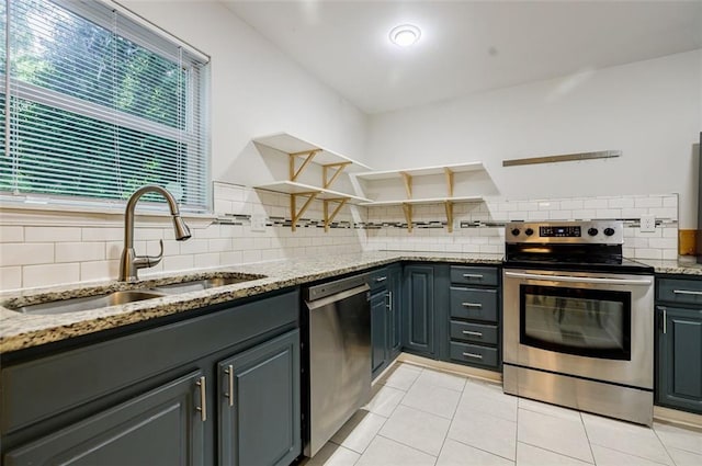 kitchen featuring sink, light stone counters, stainless steel appliances, and light tile patterned floors