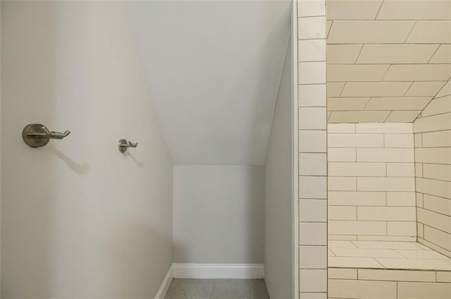 bathroom featuring a tile shower and lofted ceiling