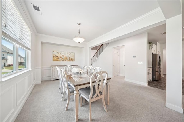 dining space with light colored carpet, crown molding, visible vents, and stairway