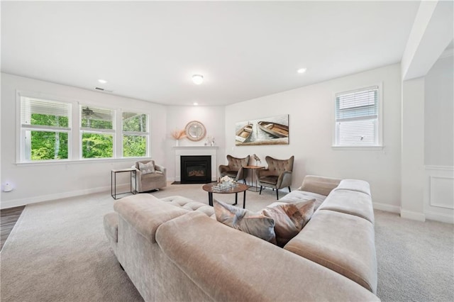 carpeted living area with a fireplace with flush hearth, baseboards, recessed lighting, and visible vents