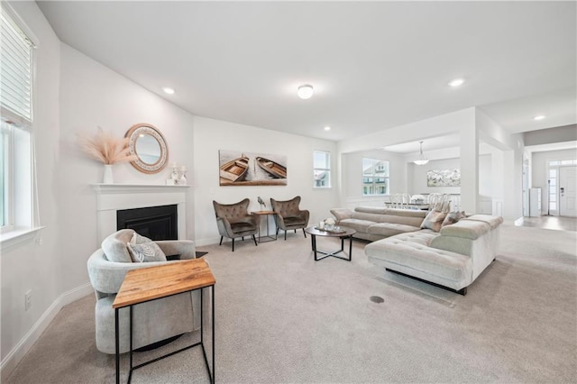 living area featuring baseboards, carpet, a healthy amount of sunlight, and a fireplace