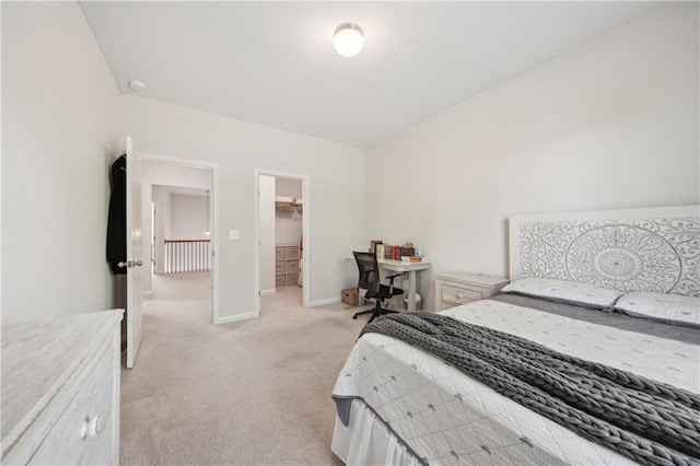 bedroom with baseboards, a walk in closet, and light carpet