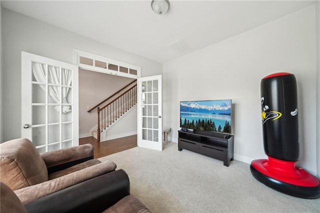 carpeted living area featuring stairway, baseboards, and french doors