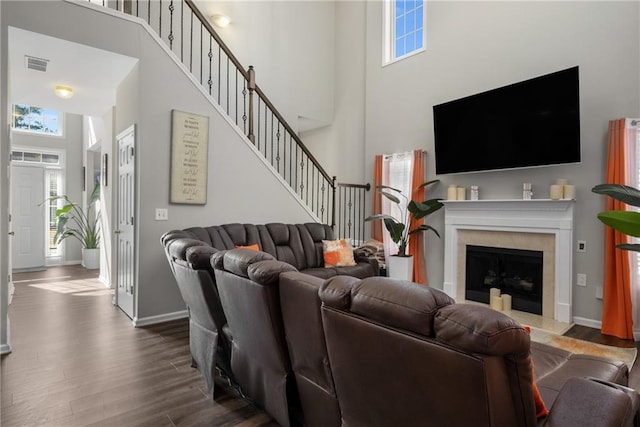 living area with visible vents, plenty of natural light, dark wood finished floors, and stairway