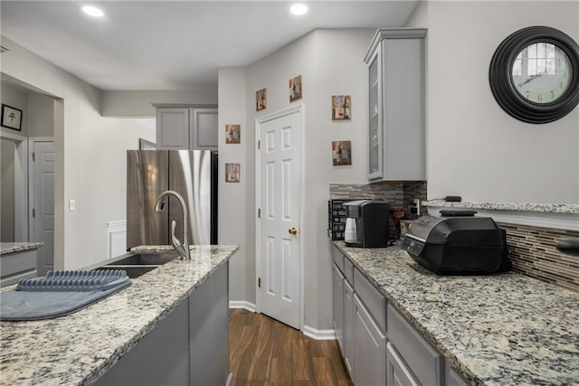 kitchen with gray cabinetry, freestanding refrigerator, and a sink