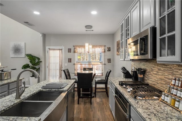 kitchen with dark wood-style floors, gray cabinets, a sink, decorative backsplash, and appliances with stainless steel finishes