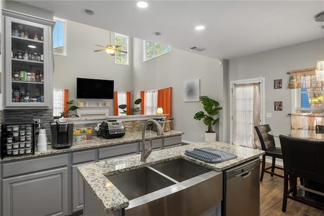 kitchen featuring visible vents, gray cabinetry, a sink, stainless steel dishwasher, and dark wood finished floors