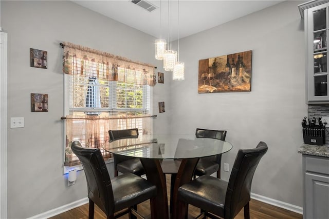 dining area with dark wood-style floors, visible vents, and baseboards