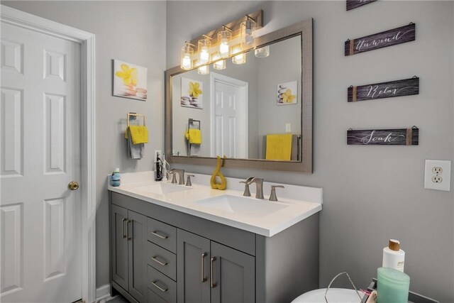 bathroom featuring double vanity, toilet, and a sink