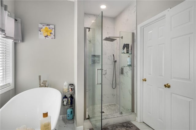 bathroom featuring marble finish floor, a marble finish shower, and a freestanding bath