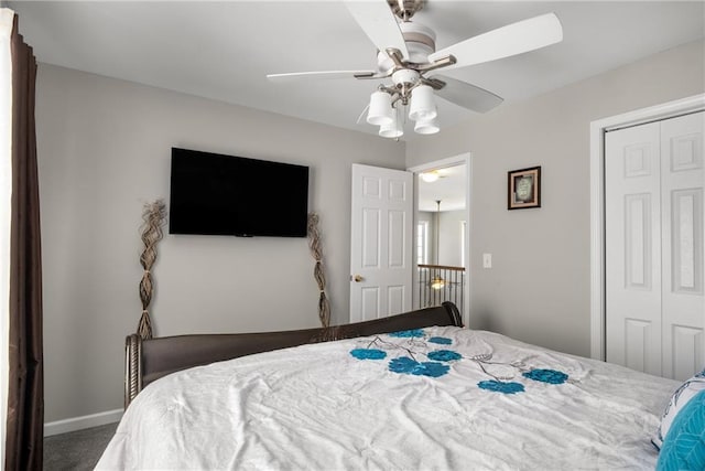 carpeted bedroom with a closet, baseboards, and ceiling fan