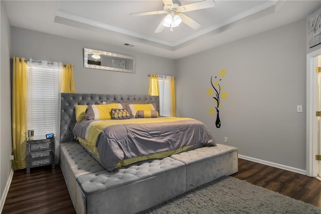 bedroom with visible vents, a raised ceiling, ornamental molding, wood finished floors, and baseboards