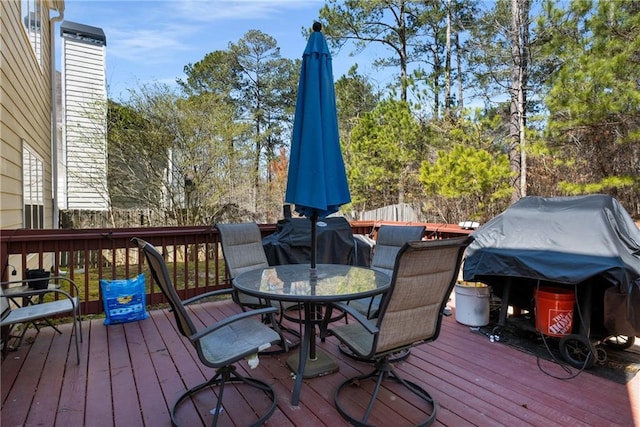 deck featuring outdoor dining area, fence, and a grill