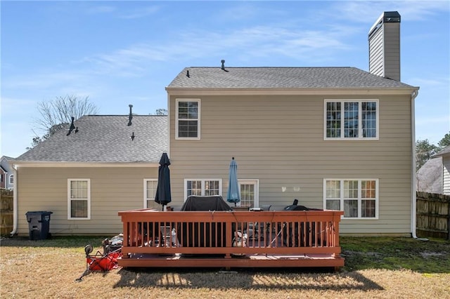 back of house featuring a deck, a chimney, roof with shingles, and fence