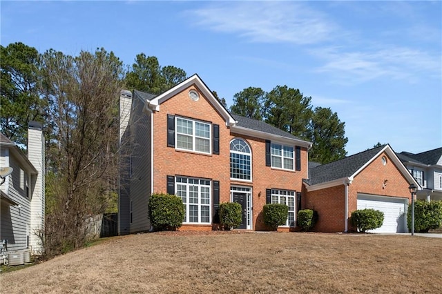 colonial home featuring a front yard, an attached garage, and brick siding