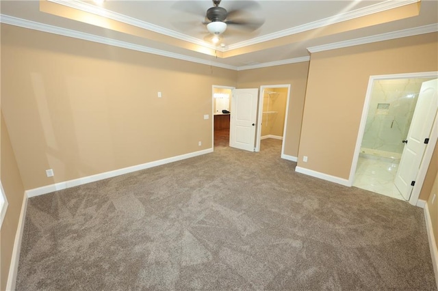 unfurnished bedroom featuring ornamental molding, ensuite bathroom, and a tray ceiling