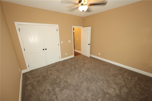 unfurnished bedroom with dark colored carpet, a closet, and ceiling fan