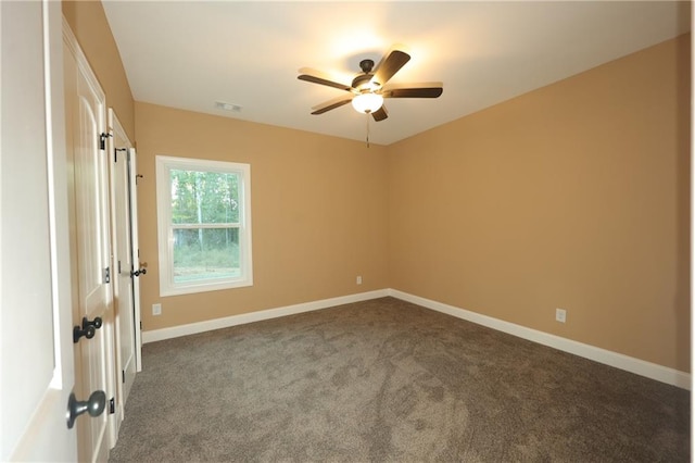 spare room with ceiling fan and dark carpet