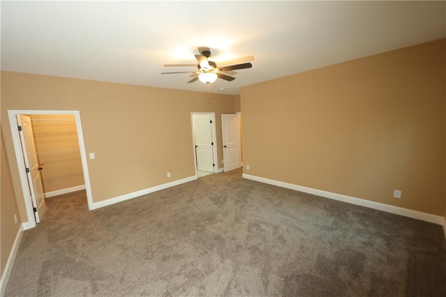 unfurnished bedroom with a closet, a spacious closet, carpet, and ceiling fan