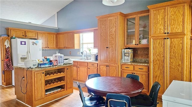 2233 Hansford Pass, Buford, GA 30519 - kitchen featuring vaulted ceiling, light countertops, light wood finished floors, glass insert cabinets, and a kitchen island