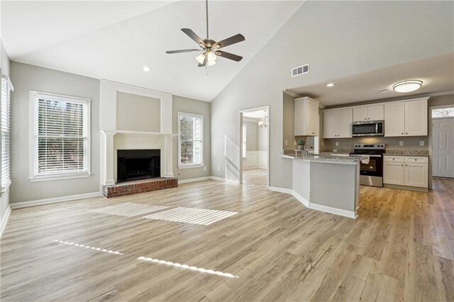 kitchen with a peninsula, a sink, visible vents, white cabinets, and appliances with stainless steel finishes