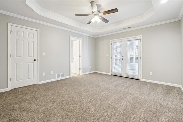 carpeted empty room featuring ornamental molding, a raised ceiling, visible vents, and french doors